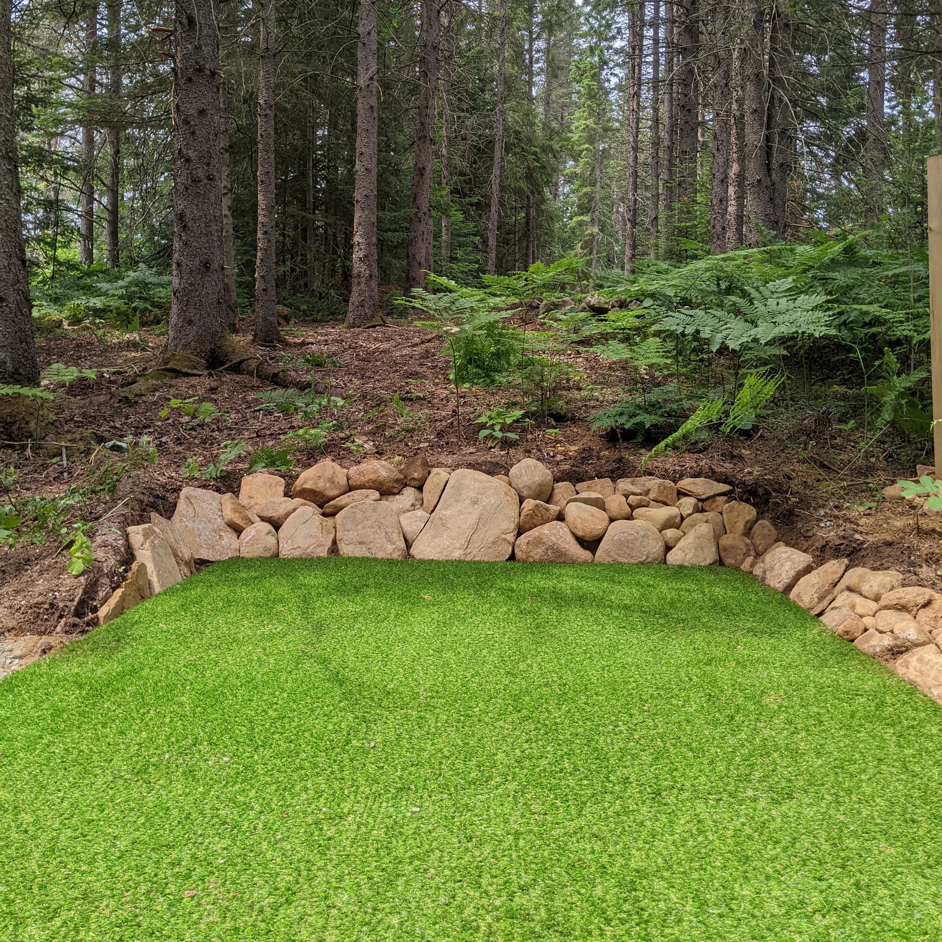 Shows a tee pad installed with artificial turf in the forest.